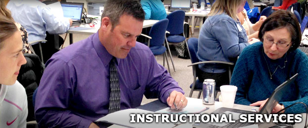 Professionals having a discussion around a table, used to represent the Instructional Services Department